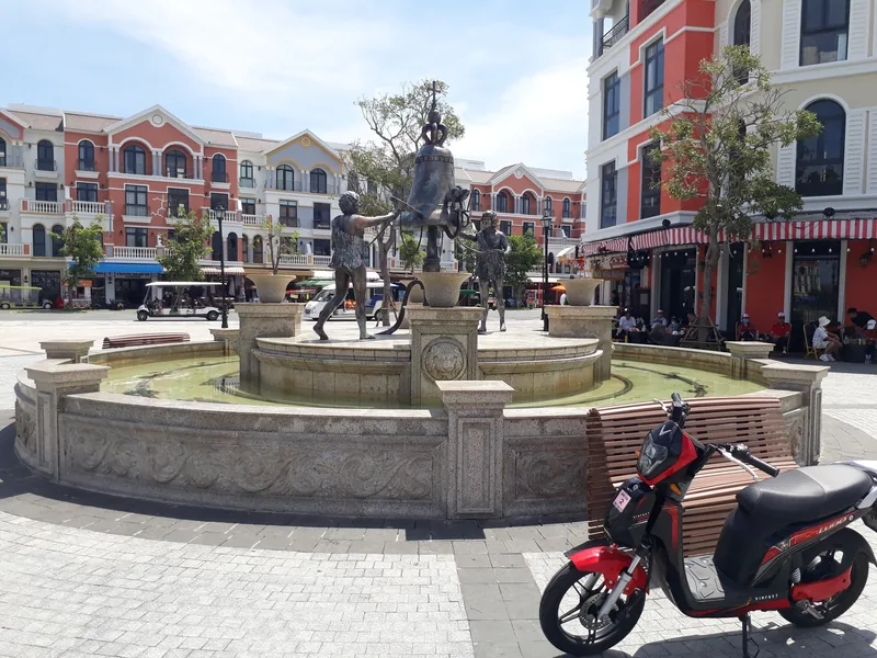 A statue fountain stands in a European-style plaza surrounded by colorful buildings in Phu Quoc's Grand World.