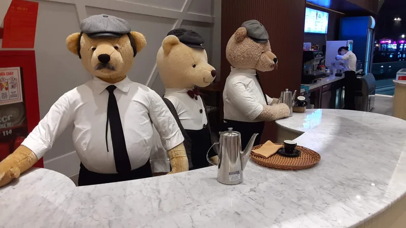 Dressed teddy bear mannequins in waistcoats and caps staff a marble coffee counter at Grand World, Phu Quoc.