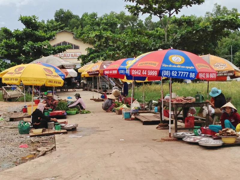 Vendors sit under colorful umbrellas selling produce and fish at a roadside market in Phu Quoc, Vietnam.