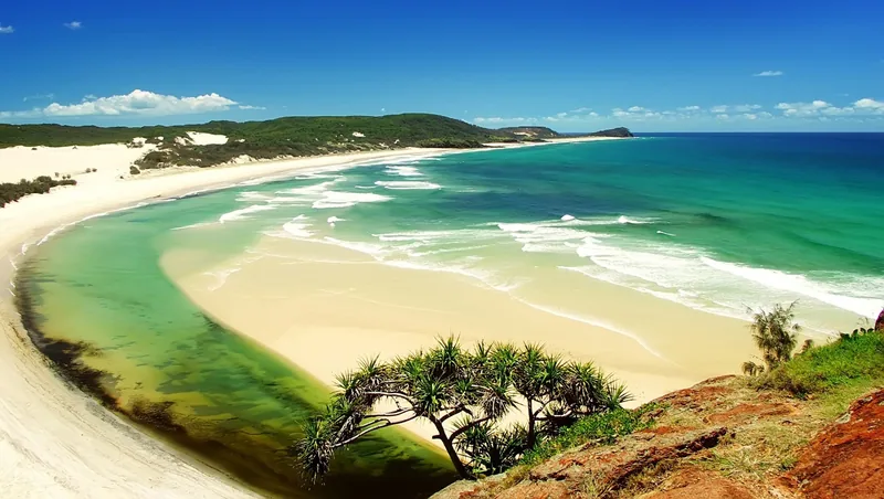 A curving sandy beach meets turquoise sea and a tidal creek near Phu Quoc's coastline.