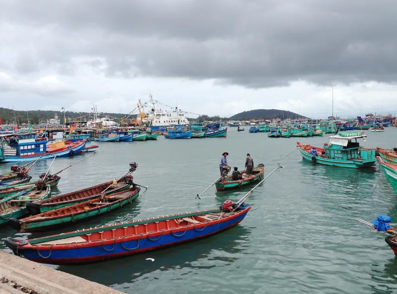 Colorful fishing boats crowd the harbor at An Thoi on Phu Quoc island under a cloudy sky.