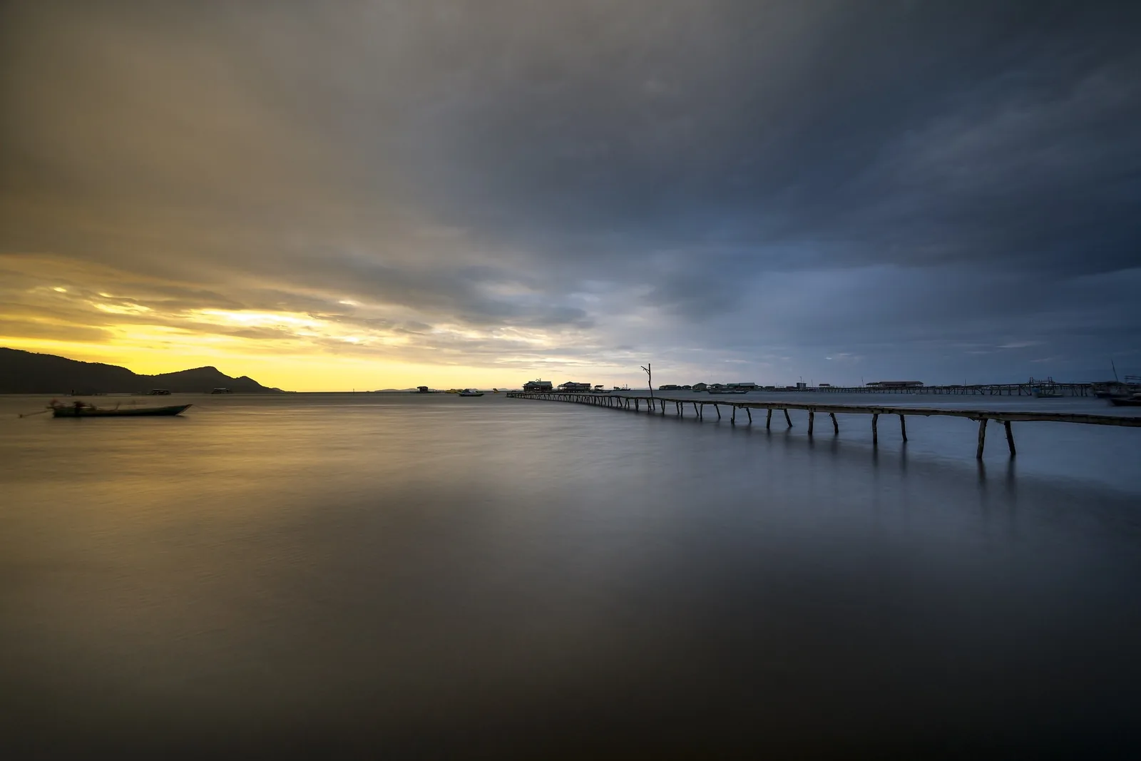 A wooden pier stretches over calm water at sunset on Phu Quoc Island. A wooden pier stretches over calm water at sunset on Phu Quoc Island.