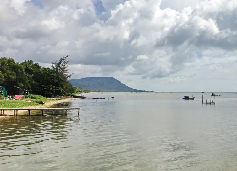 Calm coastal waters and a distant hill under cloudy skies at Ham Ninh beach, Phu Quoc.