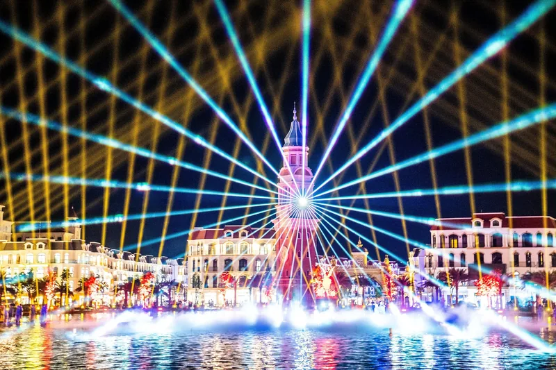 A dazzling laser and fountain light show illuminates the night sky over a clock tower at Phu Quoc United Center.