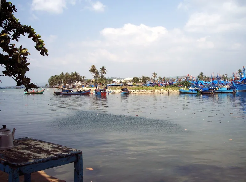 Blue fishing boats moored along a calm river with palm trees in Duong Dong, Phu Quoc.