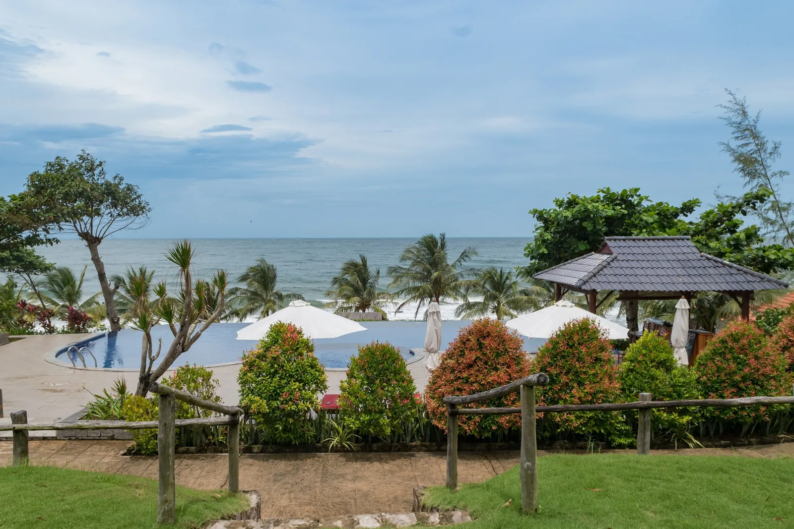 An infinity pool overlooks the sea beyond palm trees at a beachfront resort in Phu Quoc.
