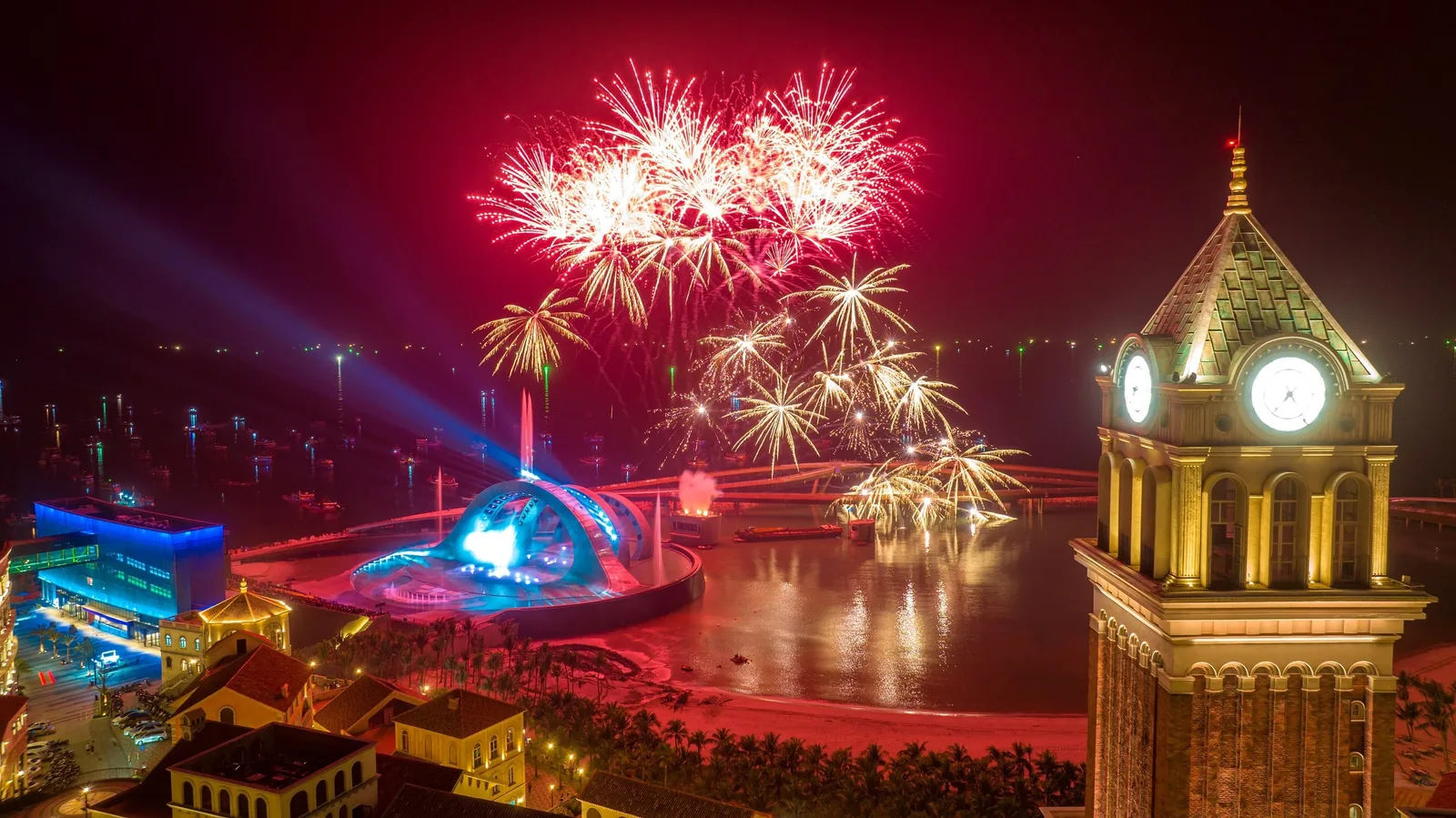 Fireworks burst red and gold over a clock tower and waterfront show in Phu Quoc at night.
