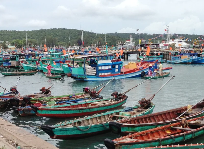 Colorful fishing boats crowd the harbor at An Thoi on Phu Quoc island under a cloudy sky.