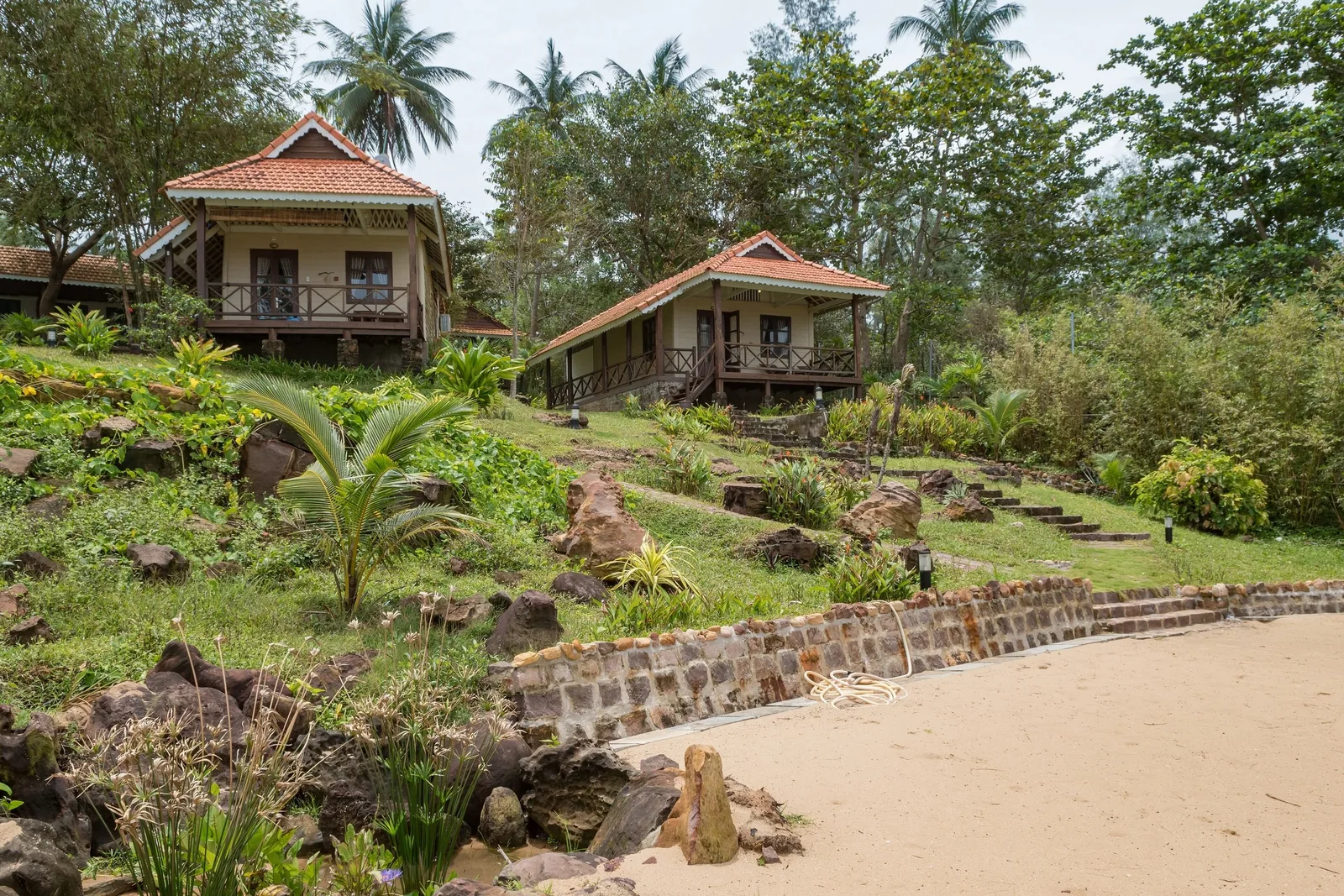 Tiled-roof bungalows sit on a lush hillside above a sandy beach in Phu Quoc.